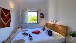 a bedroom with a bed with white sheets and a window at Villa la Bonaccia in La Maddalena