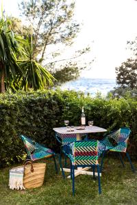 a table and chairs sitting next to the ocean at La Résidence du Bailli in Rayol-Canadel-sur-Mer