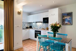 a kitchen with white cabinets and a table with blue chairs at La Résidence du Bailli in Rayol-Canadel-sur-Mer