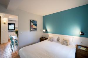 a bedroom with a white bed and a blue wall at La Résidence du Bailli in Rayol-Canadel-sur-Mer