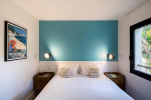 a bedroom with a white bed with a blue wall at La Résidence du Bailli in Rayol-Canadel-sur-Mer