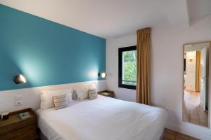 a bedroom with a large white bed with a blue wall at La Résidence du Bailli in Rayol-Canadel-sur-Mer