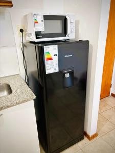 a microwave on top of a refrigerator in a kitchen at Amoblado Temporal M&S 3 L in Neuquén +25 photos