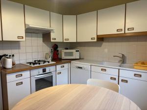 eine Küche mit weißen Schränken und einem Holztisch in der Unterkunft Appartement cosy, balcon sud, 2 chambres, parking gratuit à 10 min du centre et proche ski ! - FR-1-548-4 in Villard-de-Lans