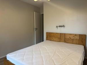 ein Schlafzimmer mit einem weißen Bett mit einem hölzernen Kopfteil in der Unterkunft Appartement cosy, balcon sud, 2 chambres, parking gratuit à 10 min du centre et proche ski ! - FR-1-548-4 in Villard-de-Lans + 1 Foto