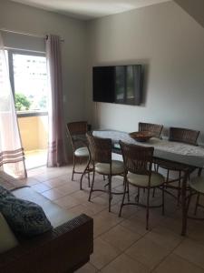 a dining room with a table and chairs and a television at Apartamento Duplex em Itapema a 250 metros do mar in Itapema