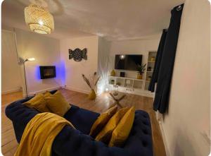 a living room with a blue couch with yellow pillows at Le nid du dernier sou in Boulogne-sur-Mer