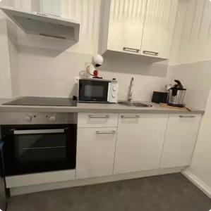 a white kitchen with a microwave and a sink at Le nid du dernier sou in Boulogne-sur-Mer