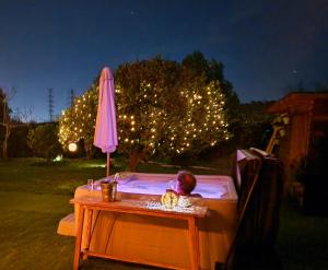 una mesa con una sombrilla junto a un árbol con luces en Casita Cártama casa rural jacuzzi, en Estación de Cártama