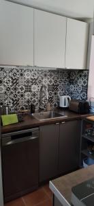 a kitchen with a sink and a tile wall at Bathy Ház in Tiszakécske