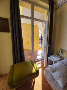 a bedroom with a green chair and a large window at Ergzotic Apartments & Room in Sombor