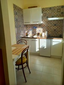 a kitchen with white cabinets and a wooden table and chair at Ergzotic Apartments & Room in Sombor