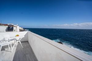 a balcony with a table and chairs and the ocean at Casa Marlene Luxury SeaFront in Güimar