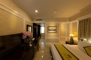 a hotel room with a bed and a desk with flowers at Anpha Boutique Hotel in Ho Chi Minh City