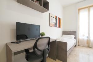 een slaapkamer met een bureau met een televisie en een bed bij PrimoPiano - Cucchi in Milaan