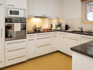 a white kitchen with white cabinets and appliances at Apartment Chalet Abendrot apARTments-28 by Interhome in Grindelwald