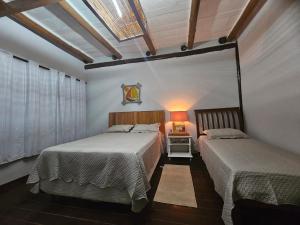 a bedroom with two beds and a table with a lamp at Hospedaria do Engenho in Niterói