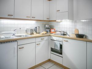 a kitchen with white cabinets and a sink at Apartment Chalet Abendrot apARTments-17 by Interhome in Grindelwald