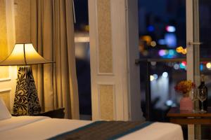 a bedroom with a bed and a lamp next to a window at Anpha Boutique Hotel in Ho Chi Minh City