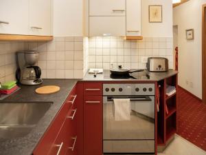 a kitchen with red cabinets and a stove top oven at Apartment Chalet Abendrot apARTments-24 by Interhome in Grindelwald