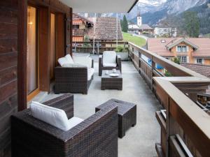 グリンデルワルトにあるApartment Chalet Abendrot apARTments-24 by Interhomeの家の上にソファと椅子付きのバルコニー