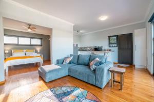 a living room with a blue couch and a bed at Eagle's Wings - Exquisite mountain view Suite in Swellendam