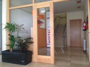 una puerta de cristal en un pasillo con una planta en Hostal El Poligono en Zamora