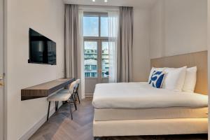 a hotel room with a bed and a desk and a television at Hotel Kobalt - Den Haag in The Hague