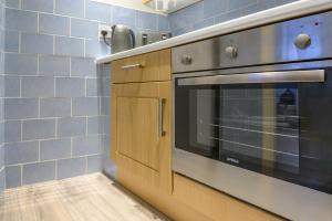 eine Küche mit Herd und blauen Fliesen in der Unterkunft Boutique Flat In Huddersfield Town Centre in Huddersfield