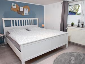 a white bed in a bedroom with a blue wall at Holiday Home An der Tanne by Interhome in Westerschoo