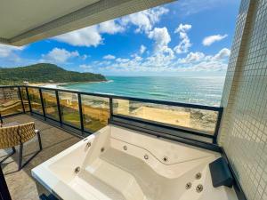 a bath tub in a room with a view of the ocean at Blue Sea Hotel in Itapema