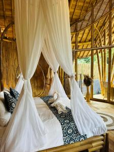 a bedroom with a canopy bed with white curtains at Bamboo House - Ecobreeze in Sidemen +170 photos