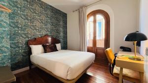 una camera da letto con un letto, una scrivania e una finestra di Santa Rita Rita B&Boutique a Talavera de la Reina