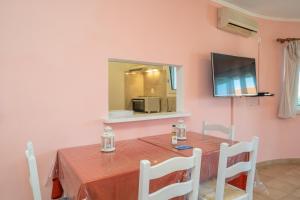 a dining room with a table and a television at Stella Hotel Apartments in Fiskardo
