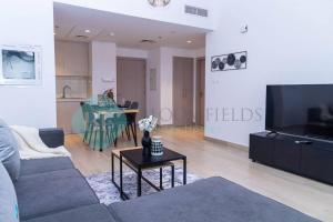 a living room with a couch and a tv and a table at Bloomfields Elegant 1br In Waters Edge Yas Island in Yas Island