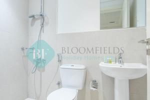 a bathroom with a toilet and a sink and a mirror at Bloomfields Metropolitan 3br In Bridges in Abu Dhabi
