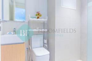 a white bathroom with a toilet and a sink at Bloomfields Metropolitan 3br In Bridges in Abu Dhabi