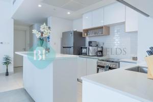 a kitchen with white cabinets and a vase of flowers at Bloomfields Metropolitan 3br In Bridges in Abu Dhabi