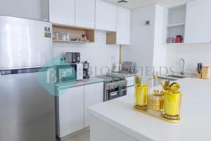 a kitchen with white cabinets and a white refrigerator at Bloomfields Metropolitan 3br In Bridges in Abu Dhabi