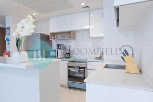 a kitchen with white cabinets and a vase of flowers at Bloomfields Metropolitan 3br In Bridges in Abu Dhabi