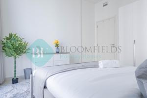 a white bedroom with a white bed and a plant at Bloomfields Metropolitan 3br In Bridges in Abu Dhabi