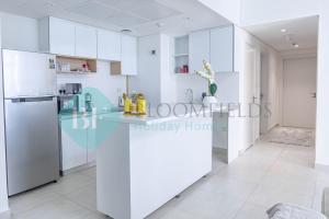 a white kitchen with a counter and a refrigerator at Bloomfields Metropolitan 3br In Bridges in Abu Dhabi