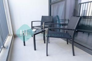 a group of chairs and a glass table on a balcony at Bloomfields Metropolitan 3br In Bridges in Abu Dhabi