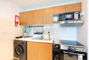 a kitchen with a sink and a washing machine at Bloomfields Premium Stu Canal View Julphar Tower in Abu Dhabi +8 photos