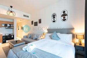 a bedroom with a white bed and a couch at Bloomfields Premium Stu Canal View Julphar Tower in Abu Dhabi