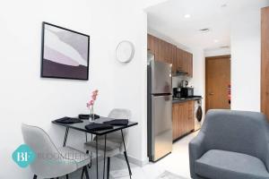 cocina con mesa, silla y nevera en Bloomfields Premium Stu In Oasis Masdar City, en Abu Dhabi Intl
