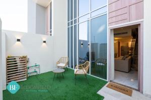 a balcony with green grass and chairs on a building at Bloomfields Premium 1br Duplex In Rukan in Nadd Shubayḩ