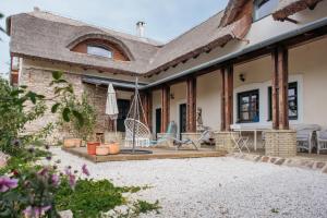 a house with a patio with chairs and a umbrella at Cselling Udvarház in Révfülöp