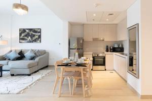 eine Küche und ein Wohnzimmer mit einem Tisch und einer Couch in der Unterkunft Bloomfields Iconic 1br Waters Edge Yas Island in Abu Dhabi