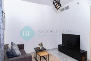 a living room with a couch and a tv at Bloomfields Luxury 1br In Oasis Masdar City in Abu Dhabi